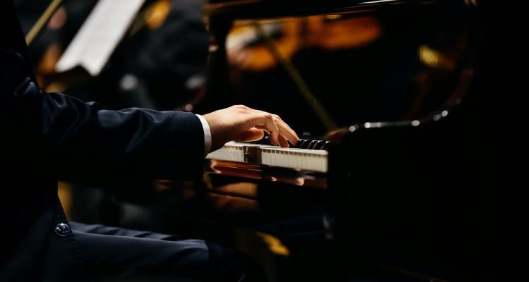 hand playing piano with string instrument in piano reflection