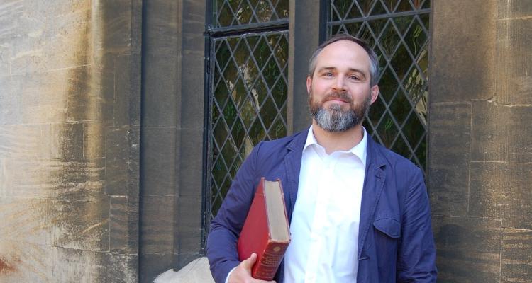 Dr James Wade holding the Heege Manuscript (credit: University of Cambridge)