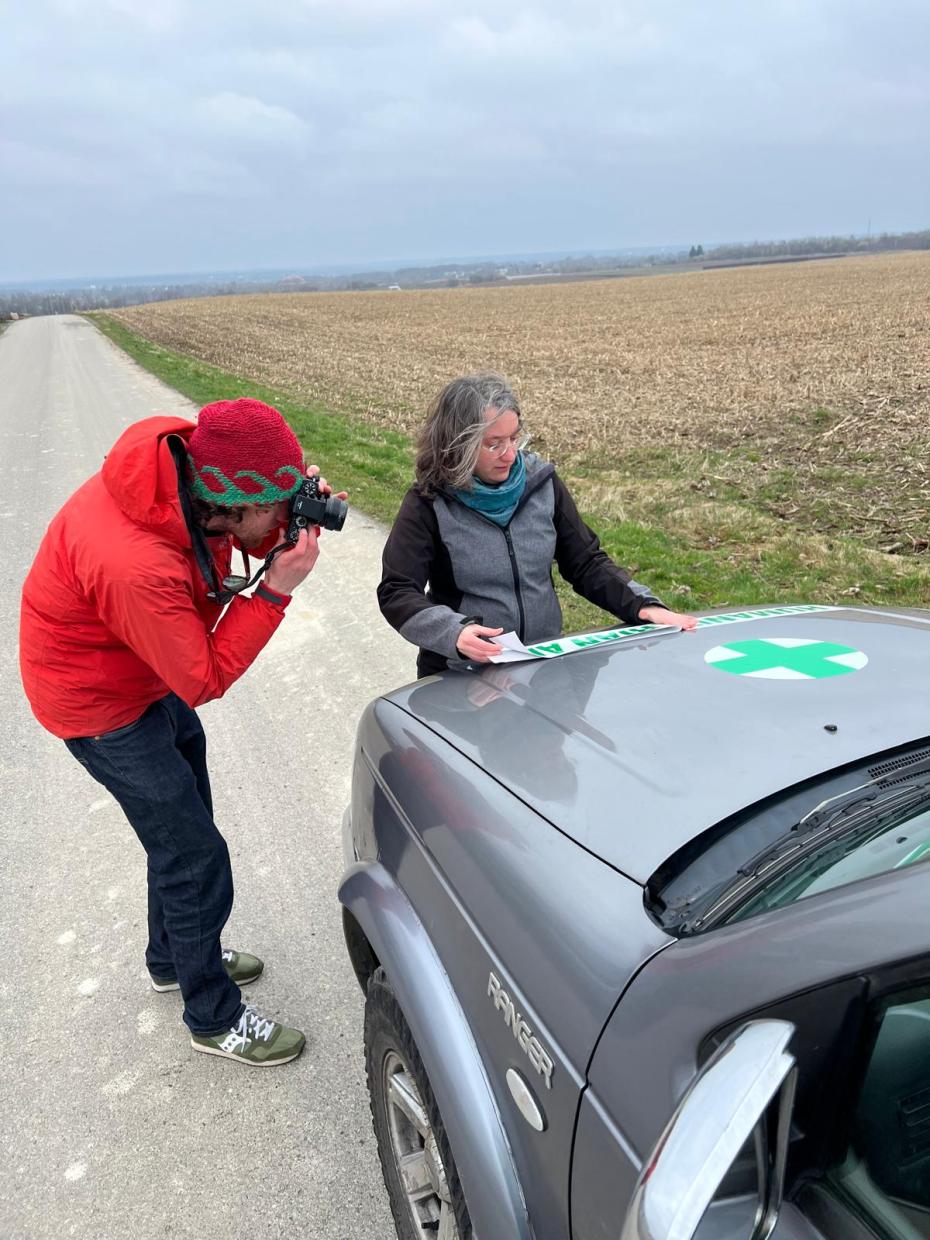 Marie-Aude looks at a map while being photographed by a man with a camera